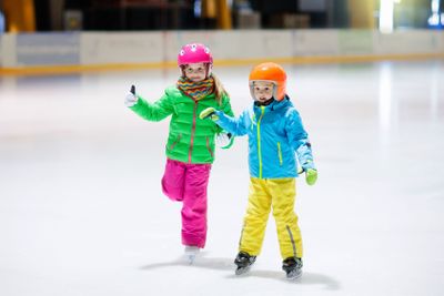Child skating on indoor ice rink. Kids skate.