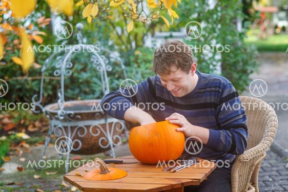 Young man making halloween pumpkin