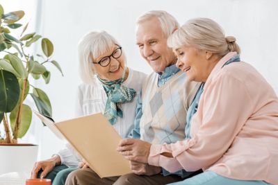 senior smiling people reading book together in nursing home