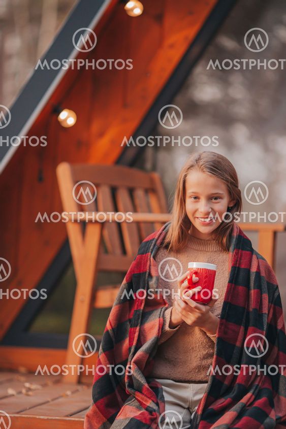 Beautiful girl wrapped in a blanket at autumn warm day