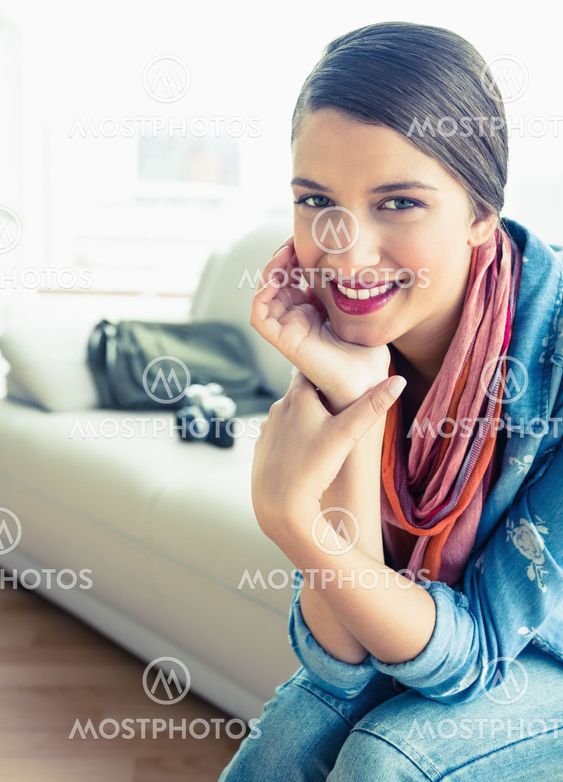 Young brunette sitting on sofa looking at camera