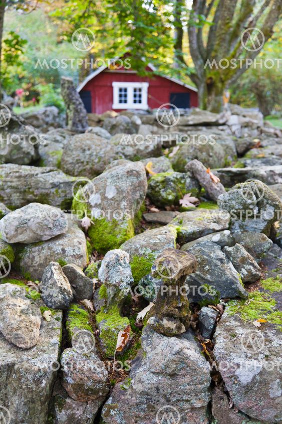 Röd stuga vid en stenmur