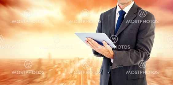 Composite image of serious charismatic businessman holding a tablet computer