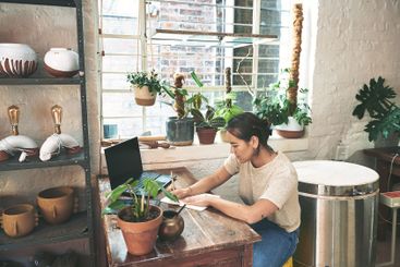 Woman, writing and book in workshop for pottery ideas,...