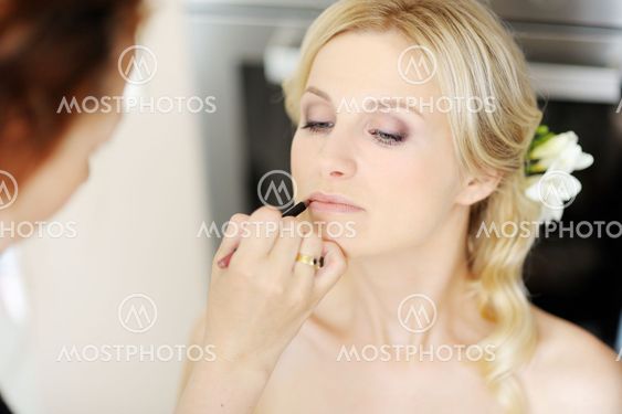 Young beautiful bride applying wedding make-up