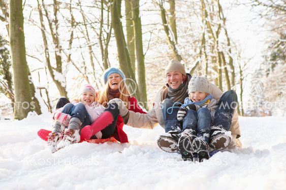 Family Sledging Through Snowy Woodland
