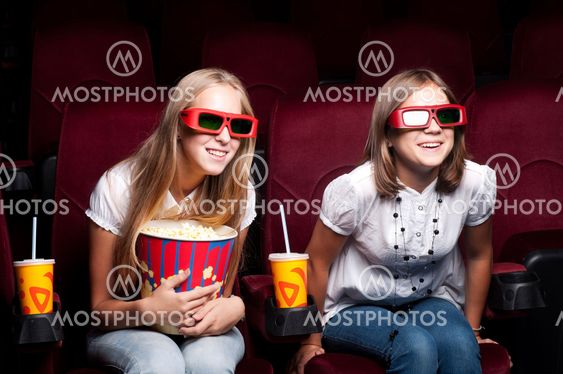 two beautiful girls watching a movie at the cinema