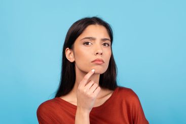 A millennial woman with brunette hair appears deep in...