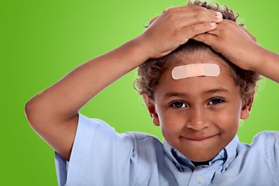 coloured little boy with plaster on his forehead against...
